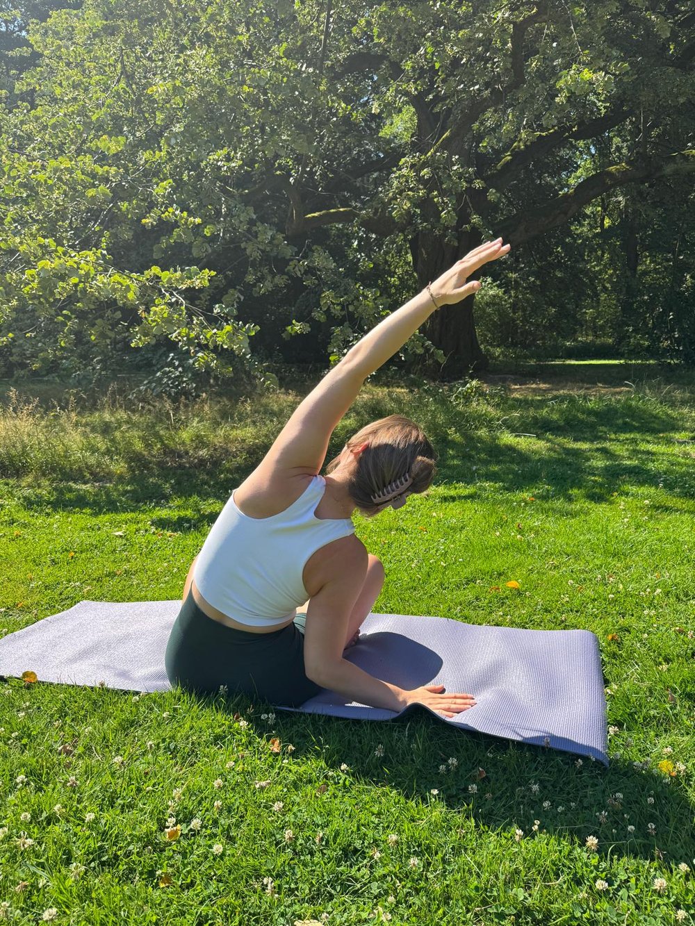 Yoga in het park — zittende houding met gestrekte armen